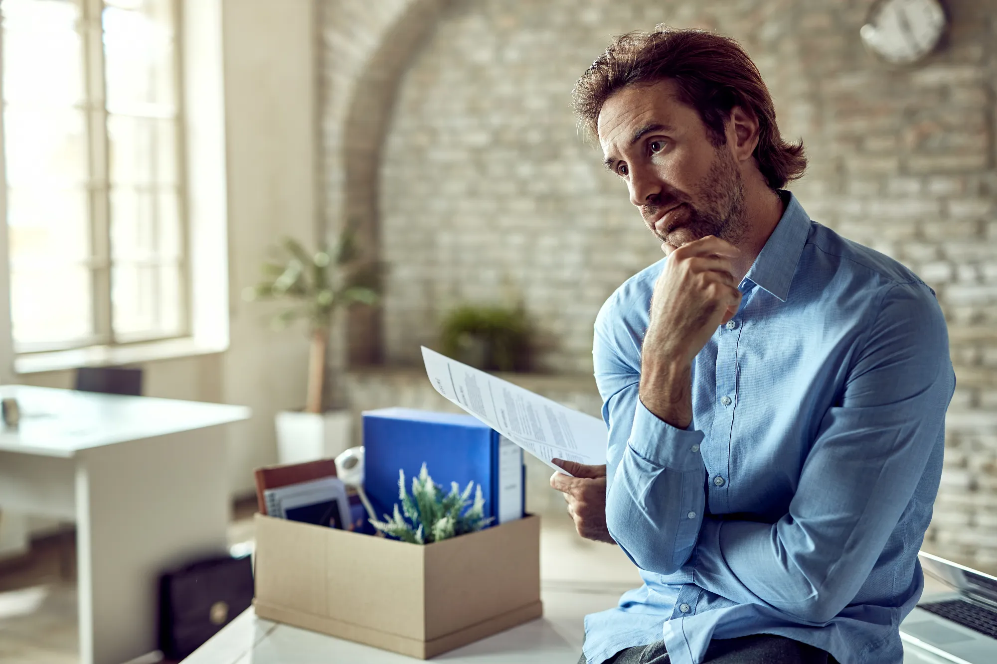 Homeowner thoughtfully reviewing blown-in insulation contractor estimates and documentation to make informed hiring decision