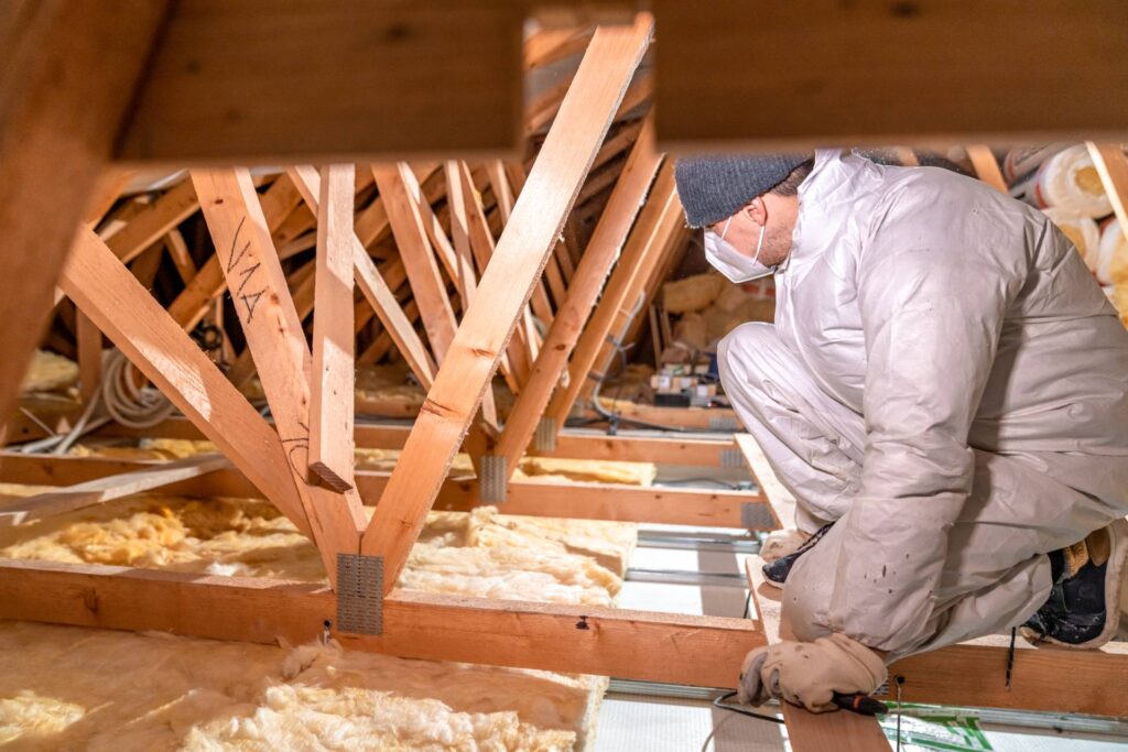 Professional licensed insulation contractor installing attic insulation with proper safety equipment and clean technique