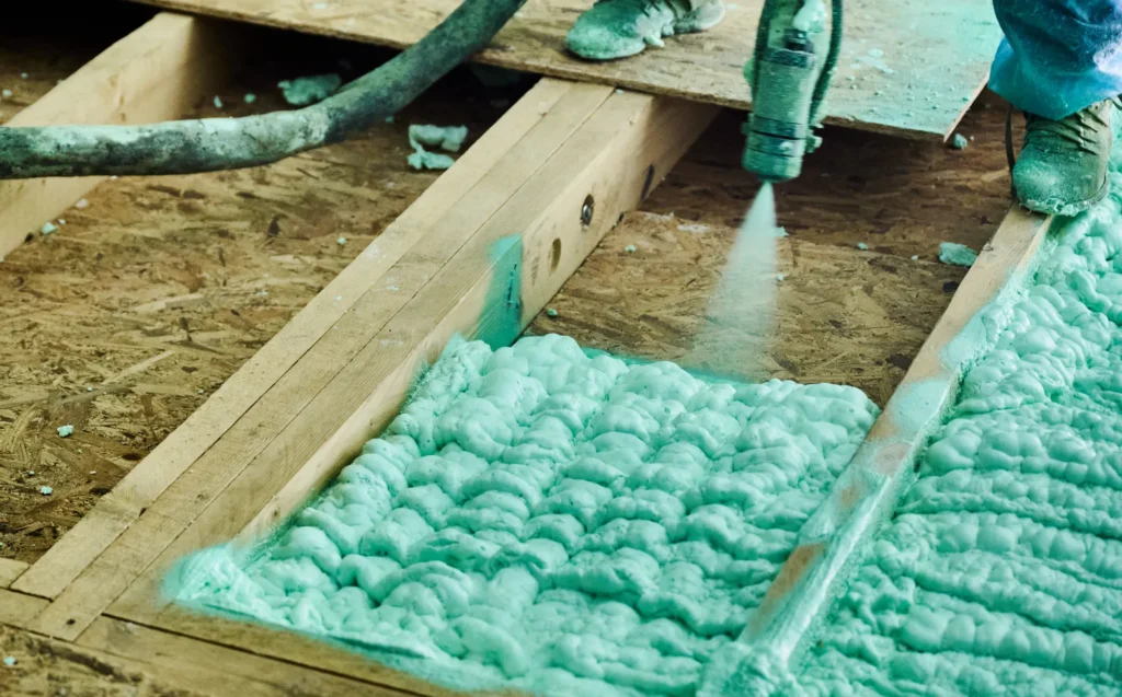 Technician applying spray foam insulation in Rockwall TX home floor joists
