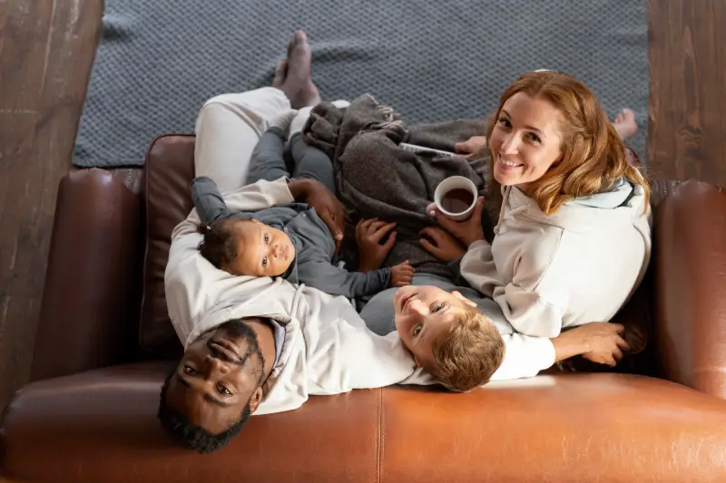 Happy family sitting together on a couch at home, enjoying comfort and warmth after an insulation service