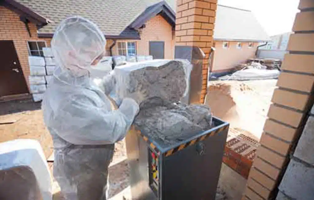 Worker in protective suit preparing cellulose insulation for a blown-in installation.