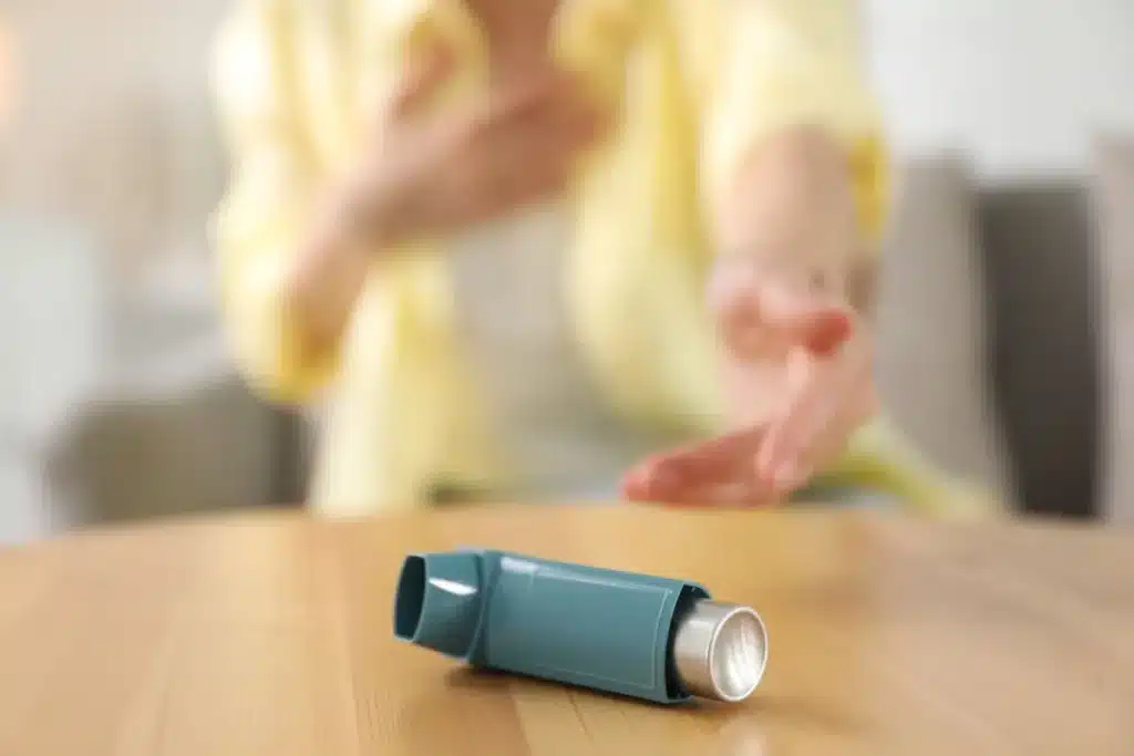 Asthma inhaler on a table representing indoor air quality and respiratory health concerns